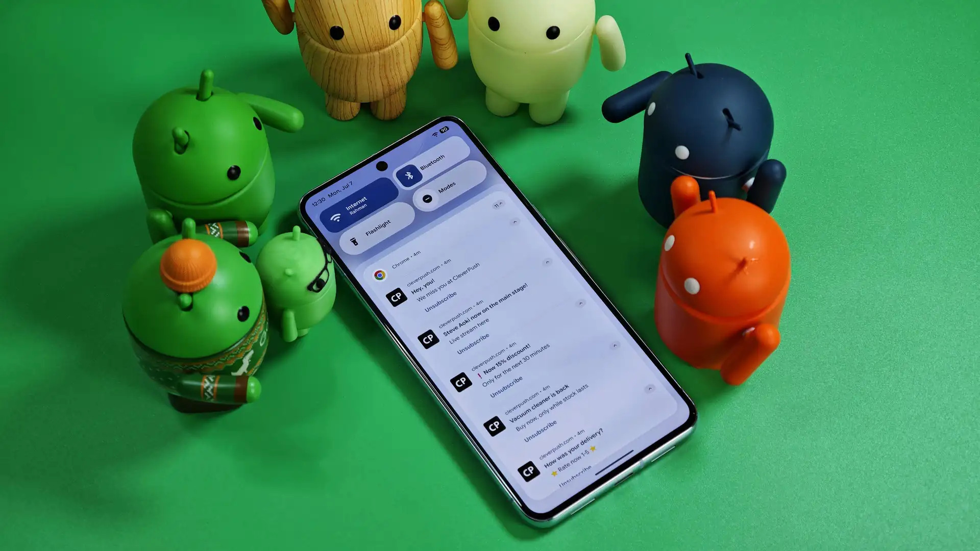 外媒曝Google为Android系统开发新功能:AI 自动分组通知类别、总结对话+群组消息! 2 Android bots standing over a Pixel phone with various notifications.jpg